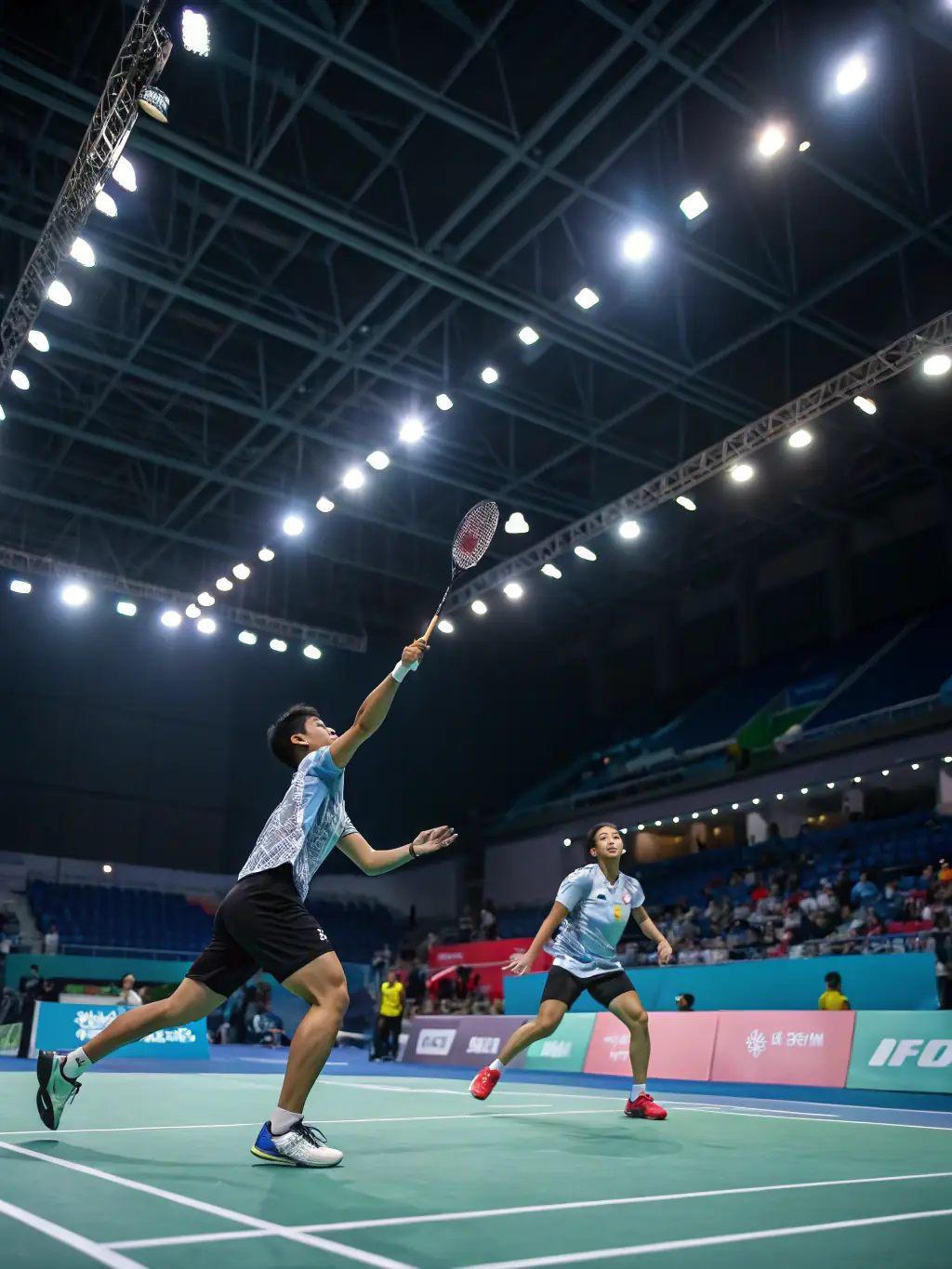 Two individuals engaged in a competitive game of badminton on an indoor court, demonstrating agility and focus at SNEVENTS-FAMILY.
